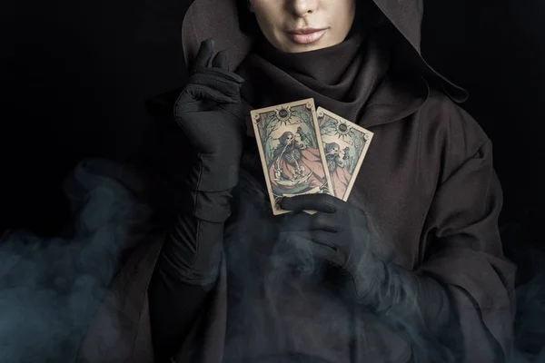 KYIV, UKRAINE - 18 AVRIL 2019 : vue recadrée de la femme en costume de mort tenant des cartes de tarot sur noir — Photo de stock