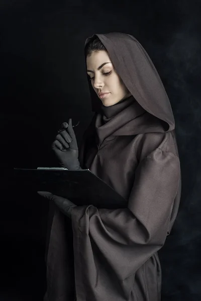 Frau im Todeskostüm hält Klemmbrett auf schwarz — Stockfoto