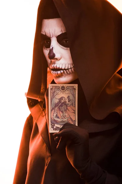 KYIV, UKRAINE - APRIL 18, 2019: woman with skull makeup holding tarot card isolated on white — Stock Photo