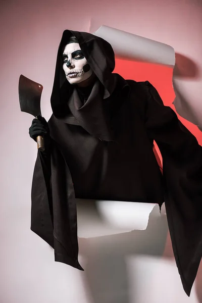 Woman in death costume holding cleaver and getting out of hole in paper — Stock Photo