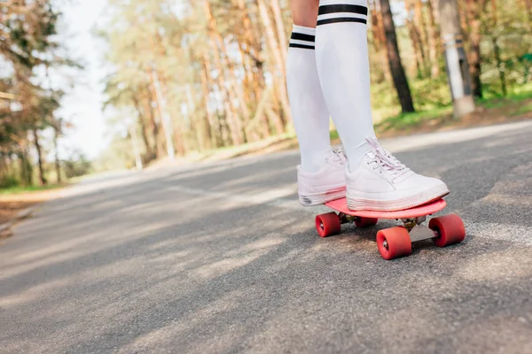 Частковий вид на дівчину в коліно шкарпетки скейтбординг на дорозі — Stock Photo