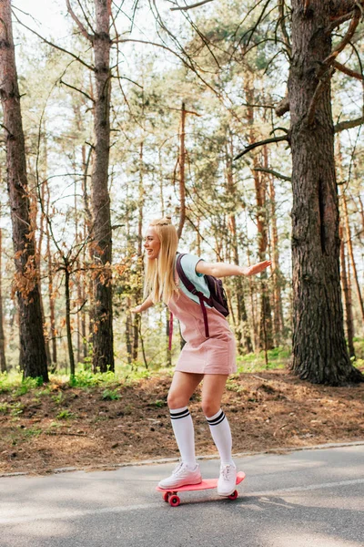 Visão de comprimento total da menina loira em meias de joelho skate na estrada — Fotografia de Stock