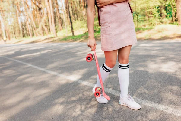 Corte vista de menina no joelho meias segurando penny board na estrada — Fotografia de Stock