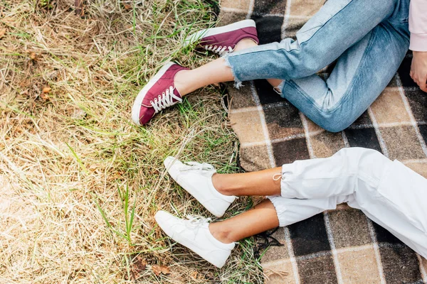 Draufsicht auf zwei multiethnische Freunde, die auf karierter Decke auf dem Boden liegen — Stockfoto