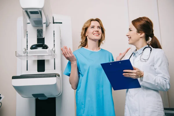Patient joyeux tout en étant debout avec le médecin radiologue près de la machine à rayons X — Photo de stock