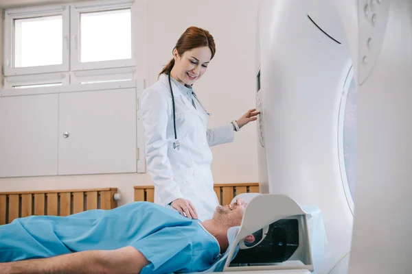 Jolie jeune radiologue préparant l'homme pour les diagnostics de tomographie dans la machine de mri — Photo de stock