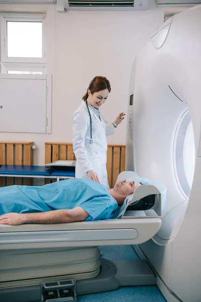 Привабливий усміхнений лікар готує чоловіка до сканування в машині Mri — стокове фото