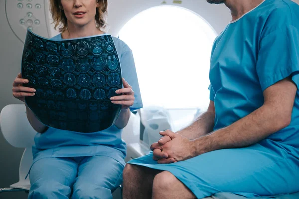 Ausgeschnittene Ansicht eines Radiologen mit Röntgendiagnose im Sitzen in der Nähe des Patienten — Stockfoto