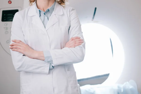 Partial view of radiologist standing with crossed arms near computed tomography scanner — Stock Photo