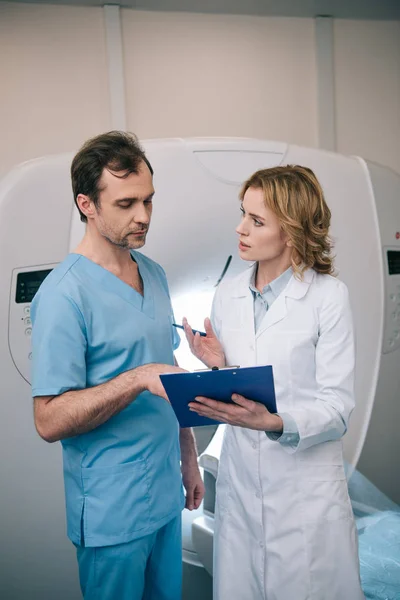 Two serious radiographers talking while examining radiology diagnosis — Stock Photo