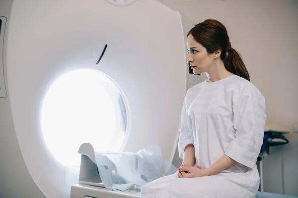 Attraktive Frau sitzt auf Computertomographie-Scanner-Bett im Krankenhaus — Stockfoto