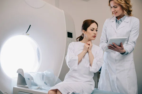 Smiling radiographer showing digital tablet with x-ray diagnosis to happy woman — Stock Photo