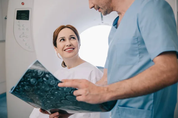 Vista recortada del médico que muestra el diagnóstico de rayos X a la mujer feliz - foto de stock