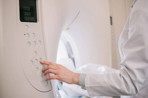 Ausschnitt eines Radiologen, der die MRI-Maschine bedient, während der Patient auf dem MRI-Scanner-Bett liegt — Stockfoto