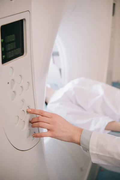 Vista parcial del radiólogo que opera el escáner de tomografía computarizada durante el diagnóstico de los pacientes - foto de stock