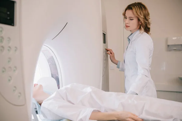 Radiografía atenta que opera el escáner del ct durante diagnósticos de la tomografía de los pacientes - foto de stock