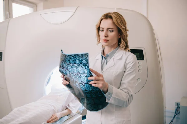 Radiólogo reflexivo que examina el diagnóstico de la tomografía durante el diagnóstico de los pacientes - foto de stock