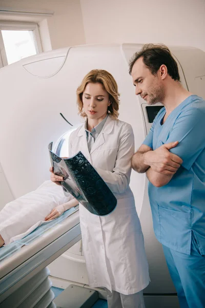 Serious doctors examining x-ray diagnosis during patients diagnostics on ct scanner — Stock Photo