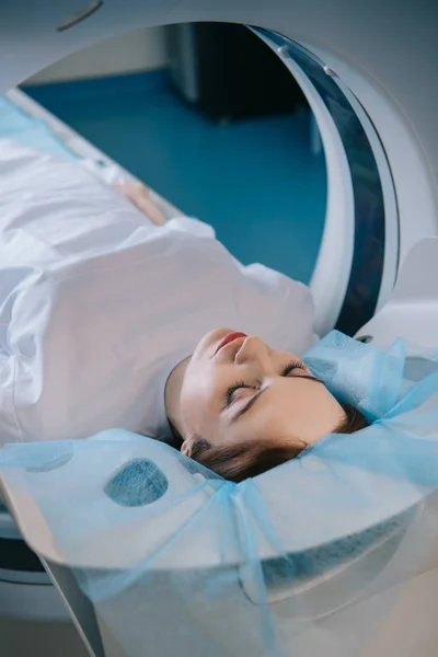 Mulher bonita deitada com os olhos fechados na cama do varredor do ct durante diagnósticos — Fotografia de Stock