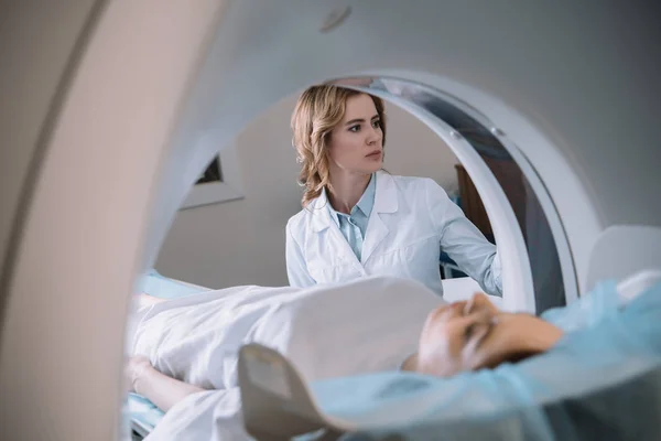 Enfoque selectivo del radiólogo atento que opera la máquina de la resonancia magnética durante diagnósticos de pacientes - foto de stock