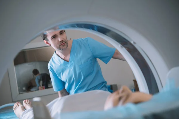 Enfoque selectivo del radiólogo atento que opera el escáner de tomografía computarizada durante el diagnóstico de los pacientes - foto de stock