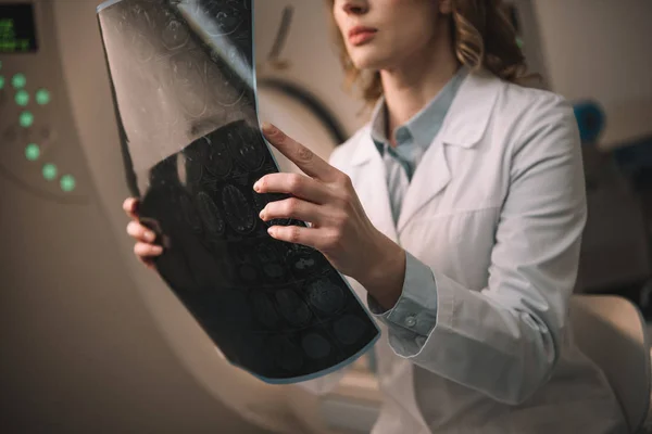 Visão recortada do radiologista segurando o diagnóstico de raios-x enquanto sentado no tomógrafo computadorizado — Fotografia de Stock