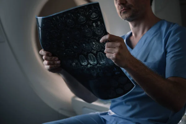 Cropped shot of radiologist examining x-ray diagnosis while sitting near ct scanner in hospital — Stock Photo