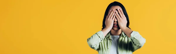 Casual brunette woman closing face isolated on yellow — Stock Photo