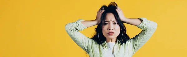 Worried asian woman holding head isolated on yellow — Stock Photo