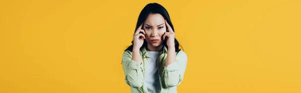 Emotional asian woman with headache isolated on yellow — Stock Photo