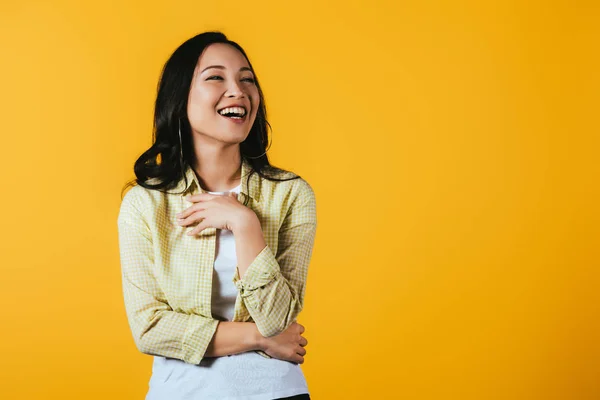 Брюнетка азиатская девушка смеется изолированно на желтый — стоковое фото