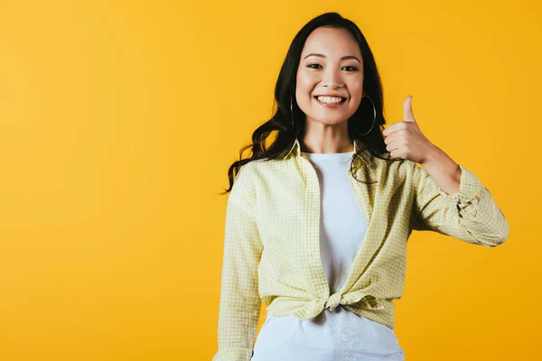 Atractivo asiático chica mostrando pulgar arriba aislado en amarillo - foto de stock