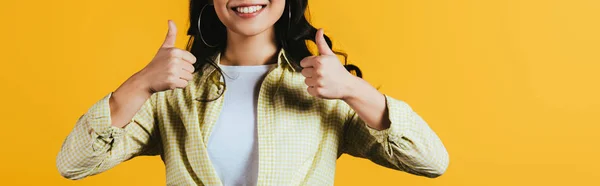 Recortado vista de sonriente chica mostrando pulgares hacia arriba aislado en amarillo - foto de stock