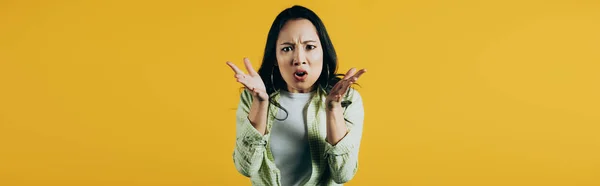 Приваблива сердита азіатська жінка жестикулює ізольовано на жовтому — стокове фото
