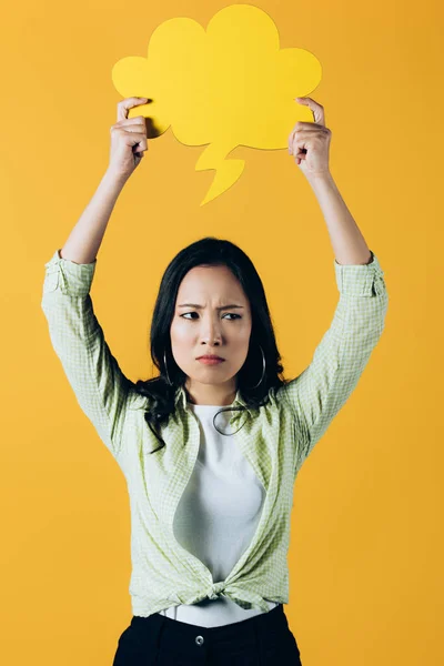 Сумна азіатська жінка тримає хмарну бульбашку мовлення, ізольована на жовтому — стокове фото