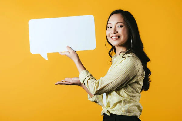 Bella sorridente ragazza asiatica presentazione discorso bolla, isolato su giallo — Foto stock