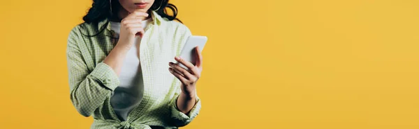 Vista recortada de chica pensativa usando teléfono inteligente aislado en amarillo - foto de stock