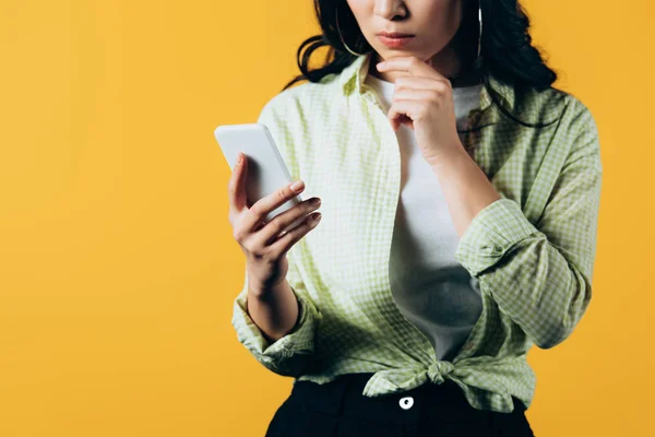 Vista recortada de chica casual usando teléfono inteligente aislado en amarillo - foto de stock