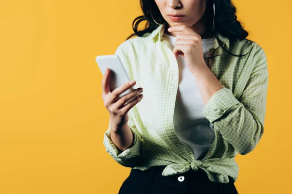 Vue recadrée de fille décontractée en utilisant smartphone isolé sur jaune — Photo de stock