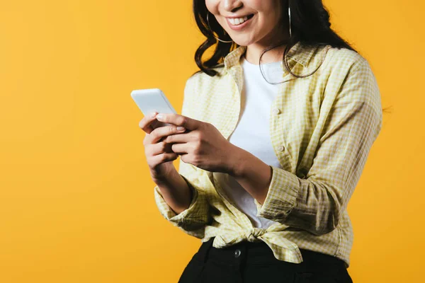 Cropped view of happy girl using smartphone isolated on yellow — Stock Photo