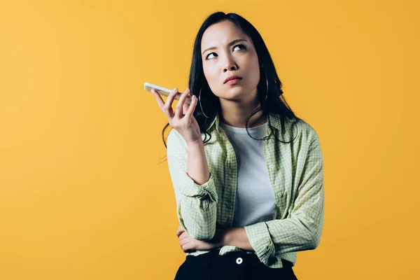 Aburrido asiático chica hablando en smartphone aislado en amarillo - foto de stock