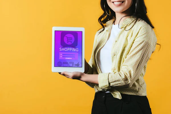 Recortado vista de chica mostrando tableta digital con aplicación de compras, aislado en amarillo - foto de stock