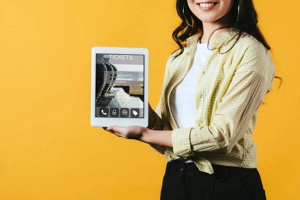 Recortado vista de chica mostrando tableta digital con tickets aplicación, aislado en amarillo - foto de stock