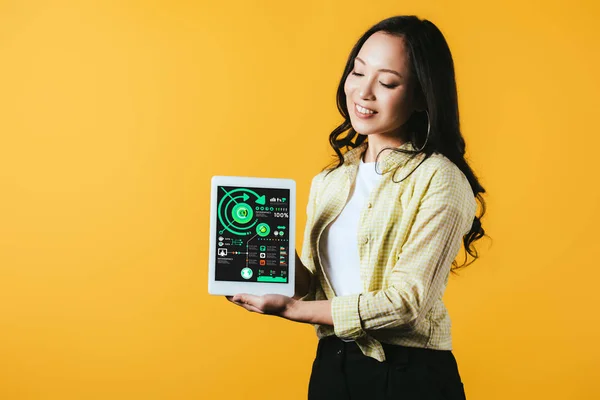 Smiling asian girl showing digital tablet with infographic, isolated on yellow — Stock Photo