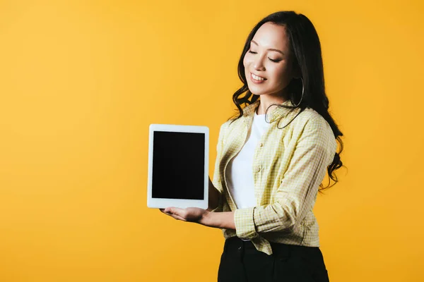 Молода азіатка, показуючи цифровий планшет з порожнім екраном, ізольована на жовтому — стокове фото