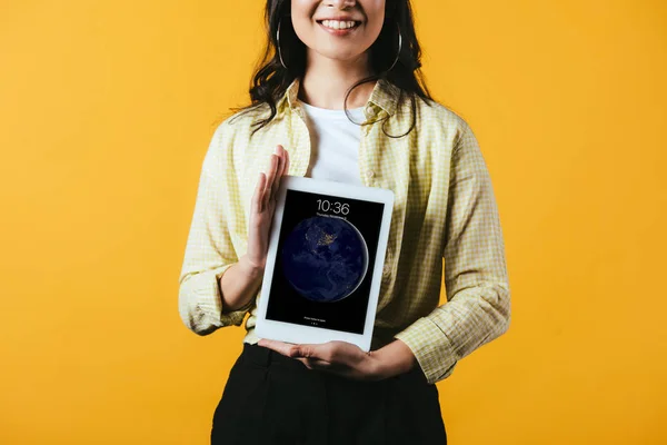 KYIV, UCRÂNIA - 16 de abril de 2019: visão recortada de menina sorridente mostrando tablet digital, isolado em amarelo — Fotografia de Stock