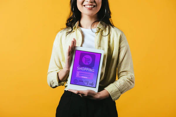 Cropped view of girl showing digital tablet with shopping app, isolated on yellow — Stock Photo