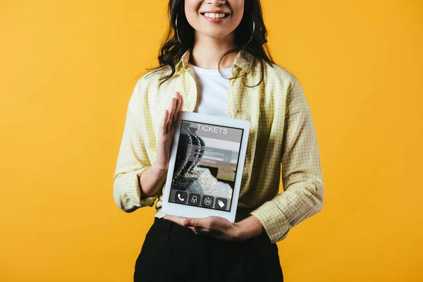 Cropped view of girl showing digital tablet with tickets app, isolated on yellow — Stock Photo