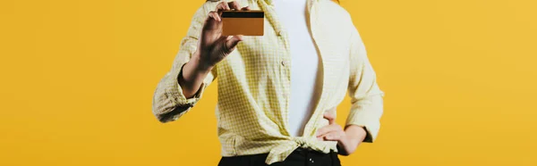 Cropped view of woman holding credit card, isolated on yellow — Stock Photo