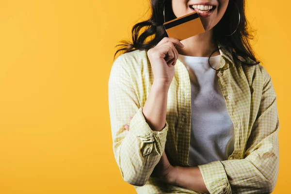 Vista ritagliata di bruna donna in possesso di carta di credito, isolato su giallo — Foto stock